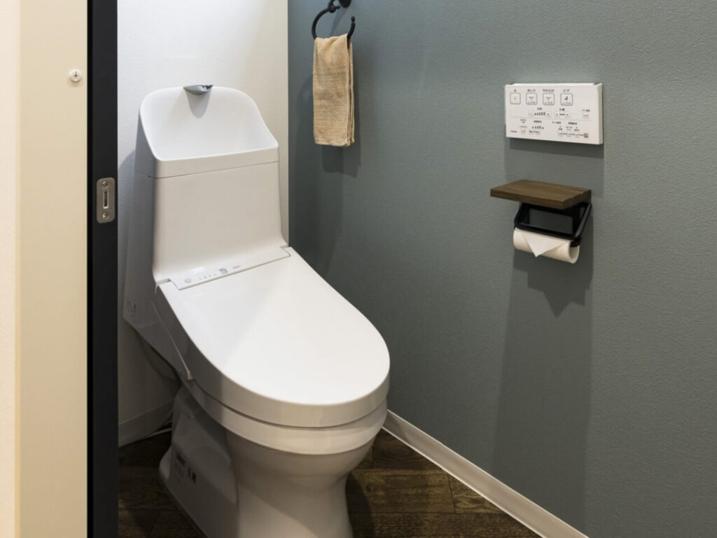 ウォシュレット付き最新型トイレと壁面リモコンのある清潔なトイレ空間