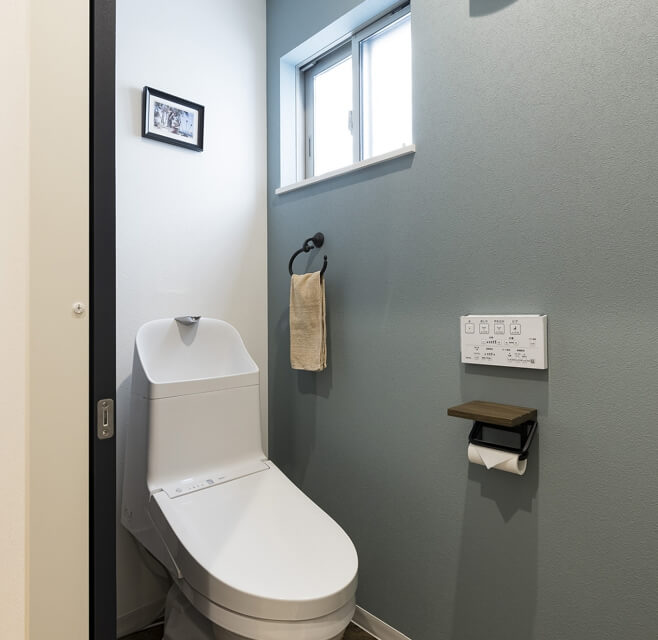 清潔感のあるトイレ空間。グレーのアクセントウォールとシンプルなデザイン